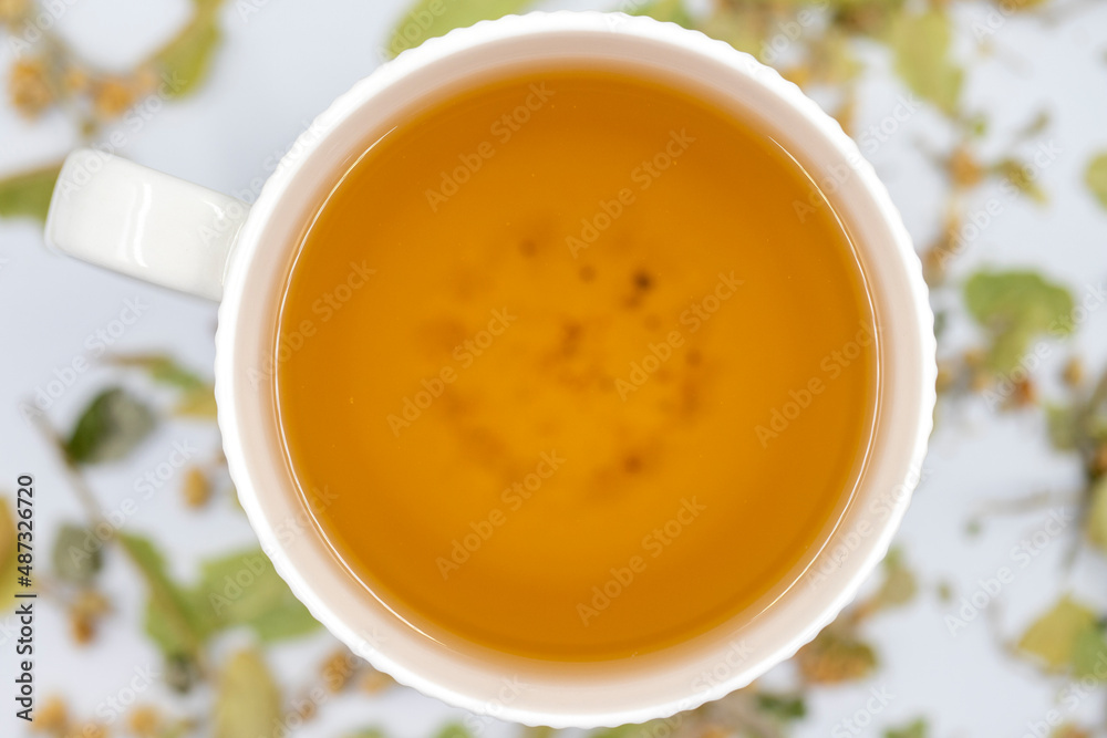 Winter Herbal tea on a white background. Linden tea. immune-boosting herbal tea. Medicinal tea prepared from linden leaves, Clove particles and Chamomile. Top view. Selective focus Winter Herbal tea on a white background. Linden tea. immune-boosting herbal tea. Medicinal tea prepared from linden leaves, Clove particles and Chamomile. Top view. Selective focus