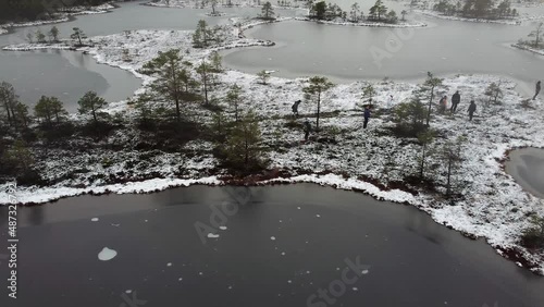 Aerial drone view of people walking with snowshoes between the bog lakes during winter. Recorded in Valgeraba, Soomaa, Estonia. photo