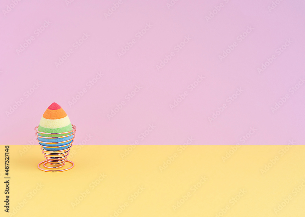 cosmetic sponge in the form of an egg on a mellifluous stand on a yellow-pink background. Copy space. cosmetic sponge in the form of an egg on a mellifluous stand on a yellow-pink background. Copy space.