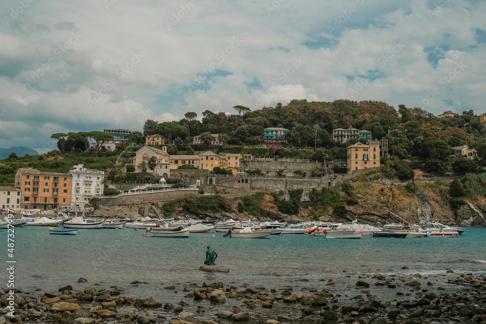 Scenic marina view of monument Il Pescatore of the Leonardo Lustig in the bay of the Silence in Sestri Levante, Liguria, Italy across the colorful houses, mountains and coastline