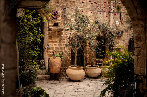 courtyard decorated with ceramic potted jugs with plants in one narrow deserted street of the old city of Tel Aviv