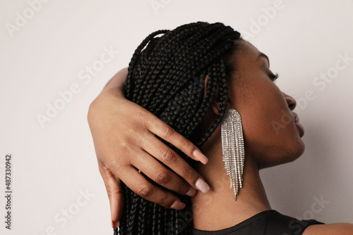 Side-view of attractive black young woman with natural make-up, over white wall.