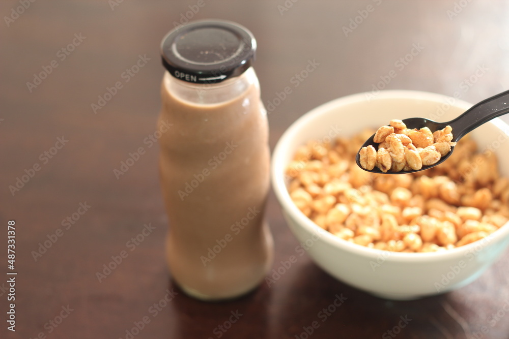cereal in a white cup with chocolate milk in a ready-to-eat glass jar Served on a brown wooden table. cereal in a white cup with chocolate milk in a ready-to-eat glass jar Served on a brown wooden table.