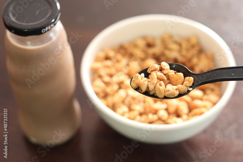 cereal in a white cup with chocolate milk in a ready-to-eat glass jar Served on a brown wooden table.