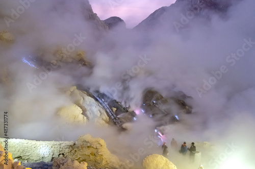 Kawah ijen volcano crater with blue flame and acid sulfuric smoke flumes view at dawn morning. Beautiful Landmark of nature adventure for traveler in East Java, Indonesia photo