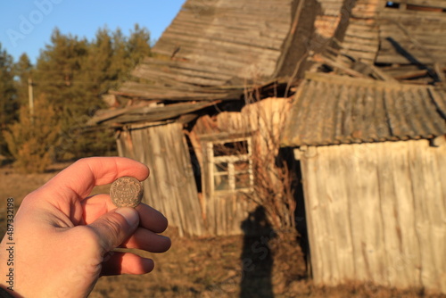 Old Austrian coin in hand against abandoned house photo