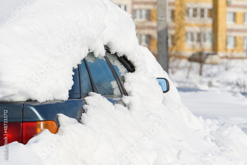 An abandoned car stands in a snowdrift. The car is covered with a thick layer of snow