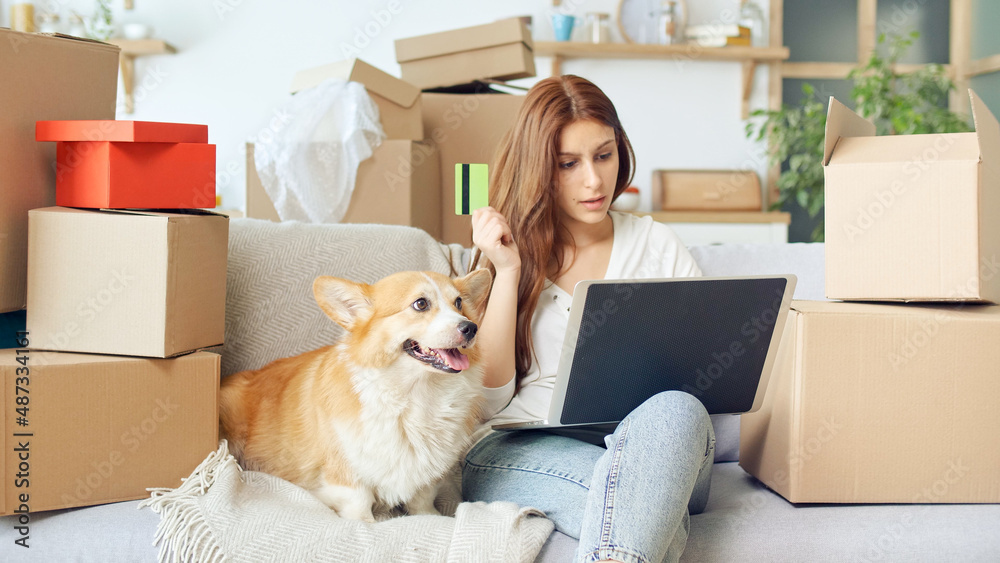 A Woman Uses a Laptop For Online Shopping at Home. Purchase Confirmation by the Internet. Binding a Card for Online Shopping. A Woman Sitting on the Couch With a Cute Dog While Online Shopping. A Woman Uses a Laptop For Online Shopping at Home. Purchase Confirmation by the Internet. Binding a Card for Online Shopping. A Woman Sitting on the Couch With a Cute Dog While Online Shopping.