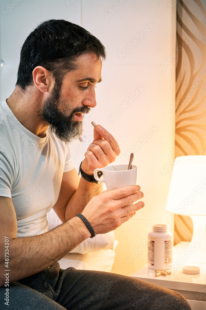 person with some kind of problem sitting on the bed and taking a pill, vertical view. person with some kind of problem sitting on the bed and taking a pill, vertical view.
