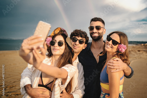 Best friends taking selfies at the beach with a rainbow in the background photo