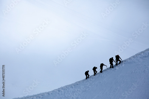 silhouette of group of climbers reaching the summit photo