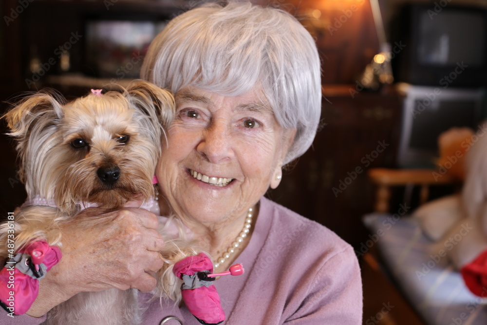 Senior woman holding little dog with pink shoes