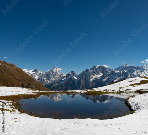 Incredibly beautiful mountain landscape: a lake in the snowy mountains, which reflects the snowy mountain peaks visible in the distance. Koruldi Lakes in Georgia