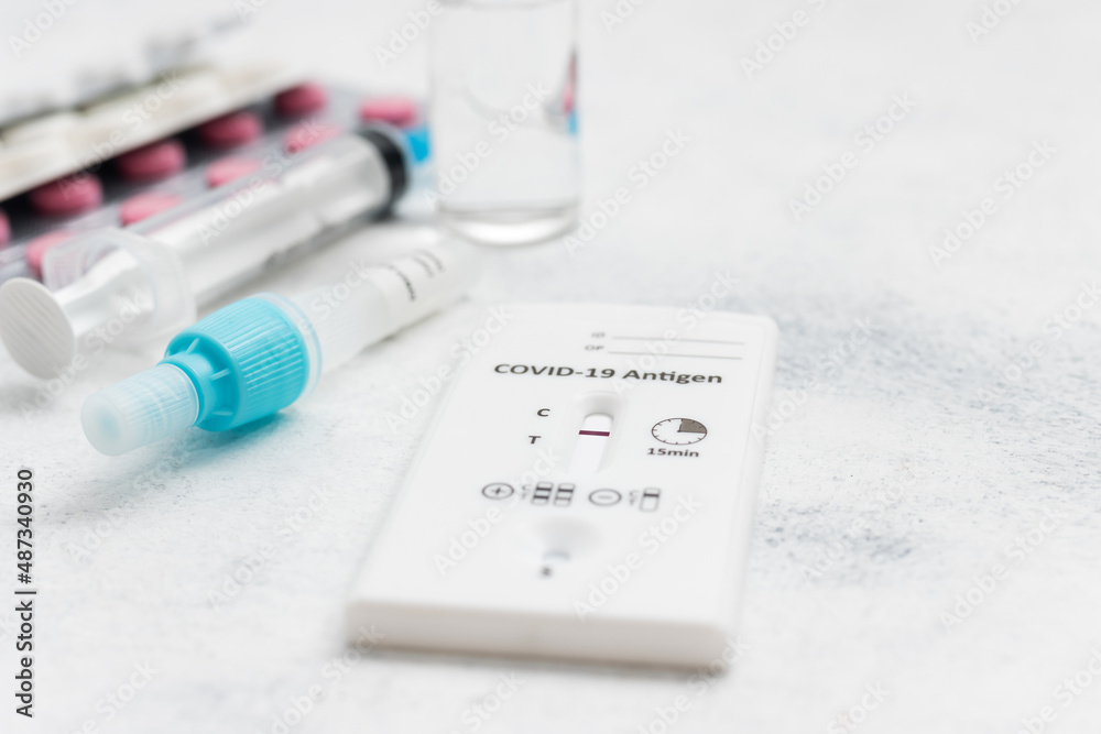 Rapid antigen test kit for viral disease COVID-19 with negative result, medicine treatment, pills and glass vial on a white background