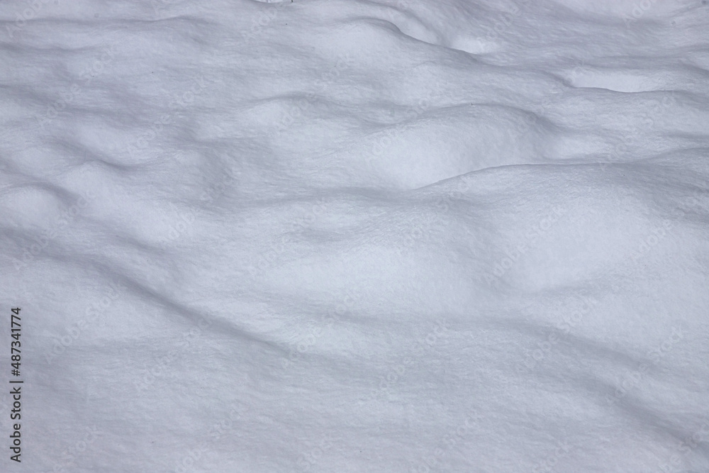 Fototapeta premium Beautiful winter background with snowy ground. Natural snow texture. Wind sculpted patterns on snow surface
