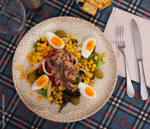 Traditional Spanish salad Xato, made from escalora, chopped salted cod anchovies olives, corn, onions boiled eggs, red . photo