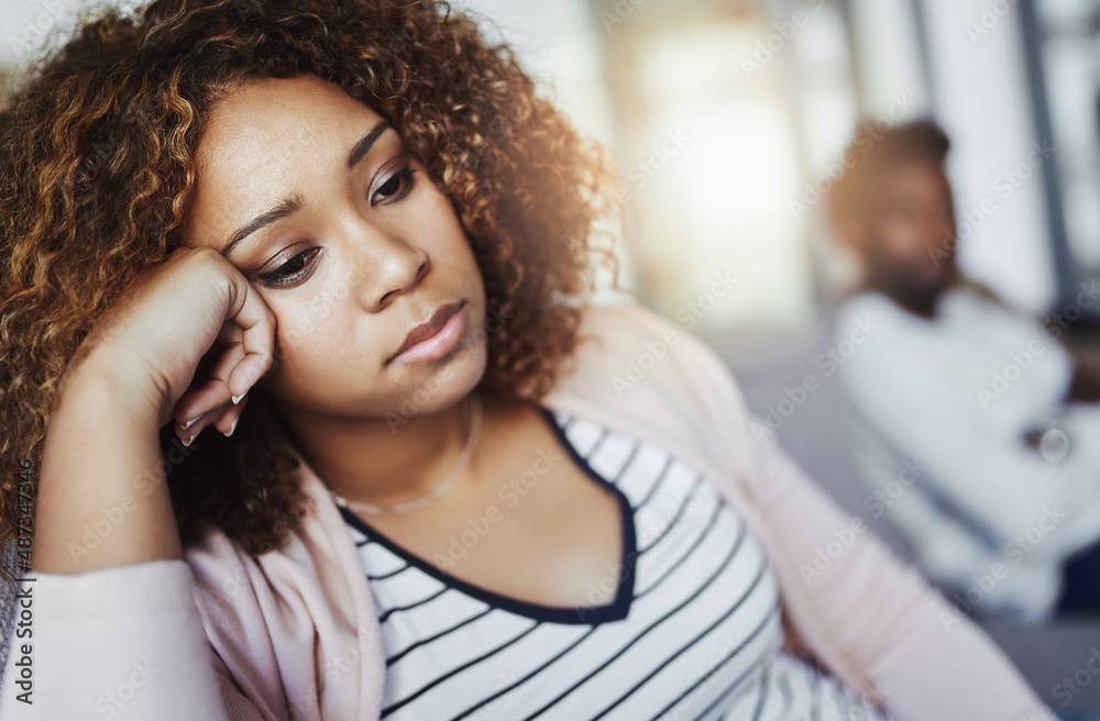 Fototapeta premium Arguments are a part of every relationship. Shot of a young woman looking despondent after having a fight with her boyfriend at home.