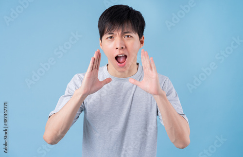 Young Asian man posing on blue background