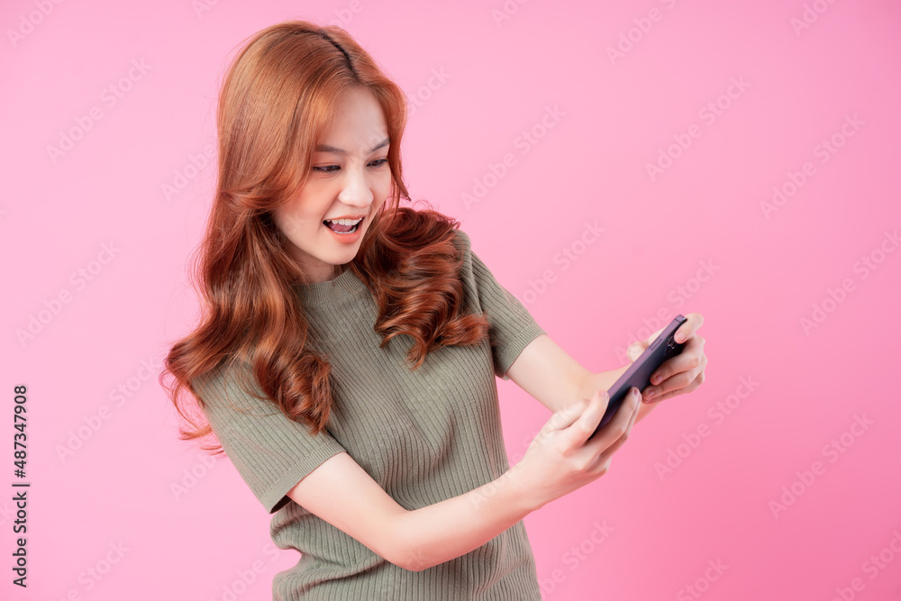 Young Asian woman using smartphone on pink background Young Asian woman using smartphone on pink background