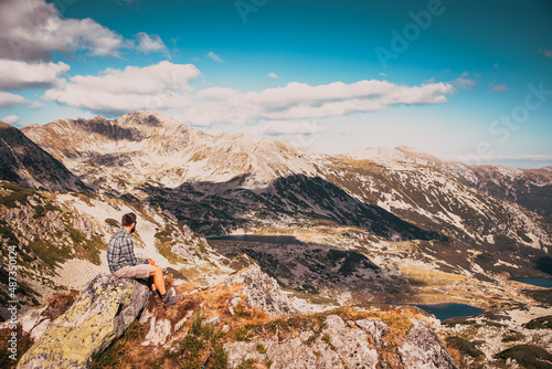 handsome man sitting on mountain top in amazing summer landscape