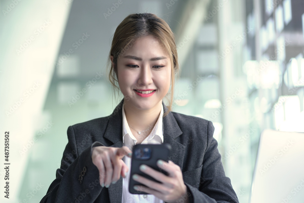 Young business Asian woman smile and looking to mobile phone, sitting at desk. Young business Asian woman smile and looking to mobile phone, sitting at desk.
