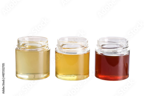honey of different varieties in glass jars stands on a white background, an isolated object