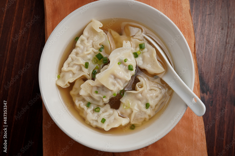 Pork dumplings boiled in clear water in a ceramic cup on a wooden table Pork dumplings boiled in clear water in a ceramic cup on a wooden table