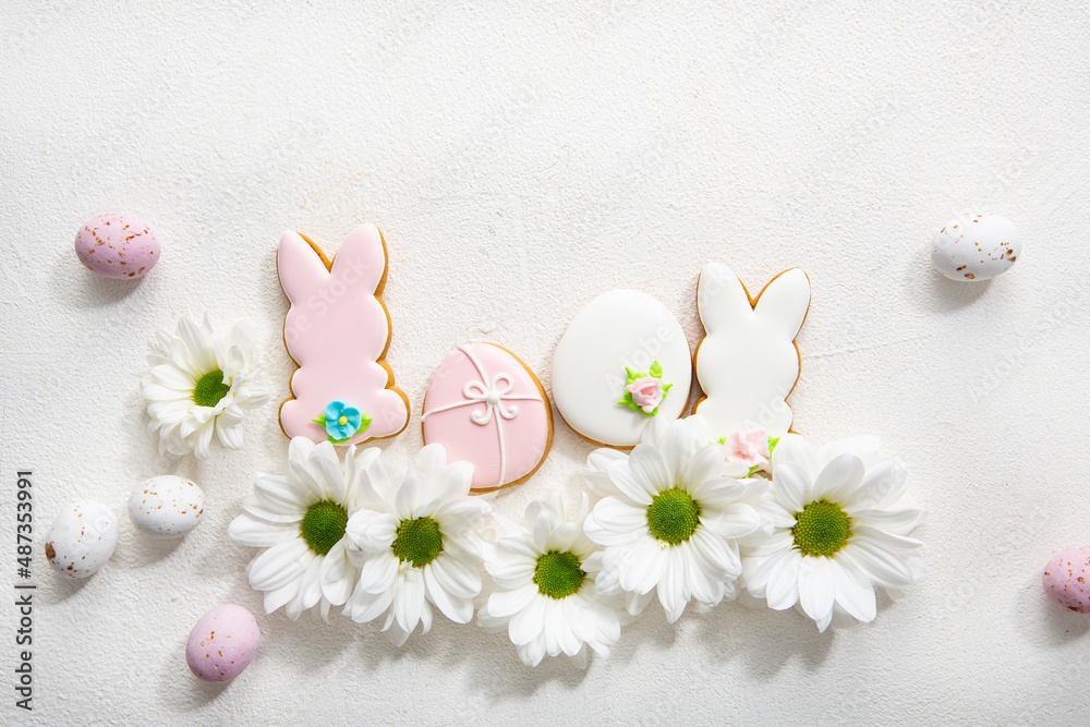 Overhead view of Easter bunny and eggs cookies and white flowers on light surface spring holiday Overhead view of Easter bunny and eggs cookies and white flowers on light surface spring holiday