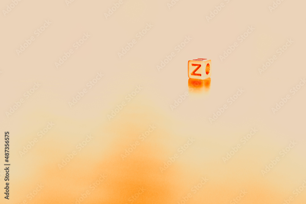 Cube shaped game dice with the orange letter Z on it on a orange ...