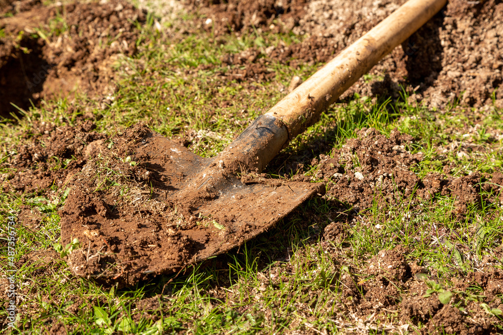 Used farming shovel with soil on it. The metal part of the shovel is in selective focus. Gardening, spring, agriculture concept. Used farming shovel with soil on it. The metal part of the shovel is in selective focus. Gardening, spring, agriculture concept.