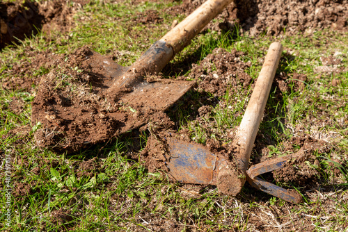 Used farming shovel and hoe with soil on it. Agricultural hoe in selective focus. Gardening, spring, agriculture concept.