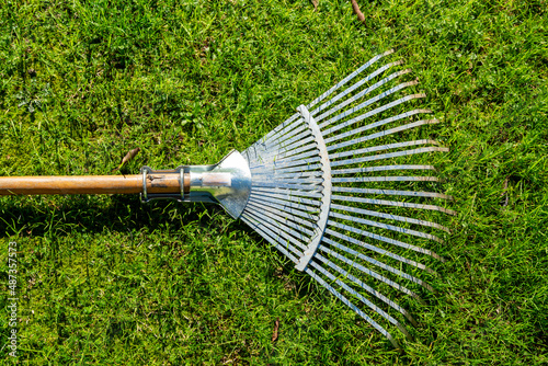 Obraz na plátne Shiny steel rake with wooden handle on fresh grass