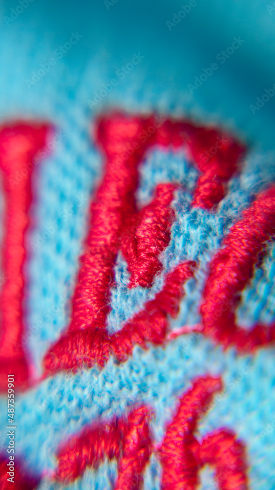 Letra E bordada con hilo rojo en tejido de algodón azul Letra E bordada con hilo rojo en tejido de algodón azul