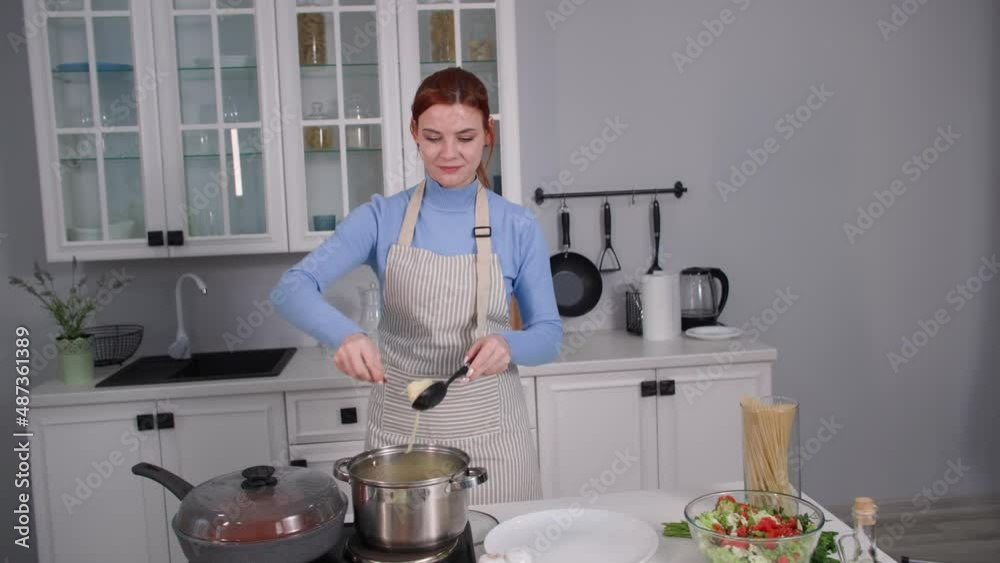 italian cuisine, charming female chef puts spaghetti on a plate to serve on the table while standing in the kitchen italian cuisine, charming female chef puts spaghetti on a plate to serve on the table while standing in the kitchen
