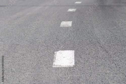 Road markings. An intermittent white stripe on an asphalt road. Urban transport