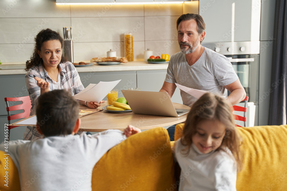 Fototapeta premium Mother addressing her children on couch during work with documents