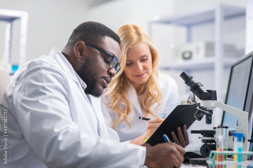 Professional team of scientists is working on a vaccine in a modern scientific research laboratory. Genetic engineer workplace. Future technology and science. Professional team of scientists is working on a vaccine in a modern scientific research laboratory. Genetic engineer workplace. Future technology and science.