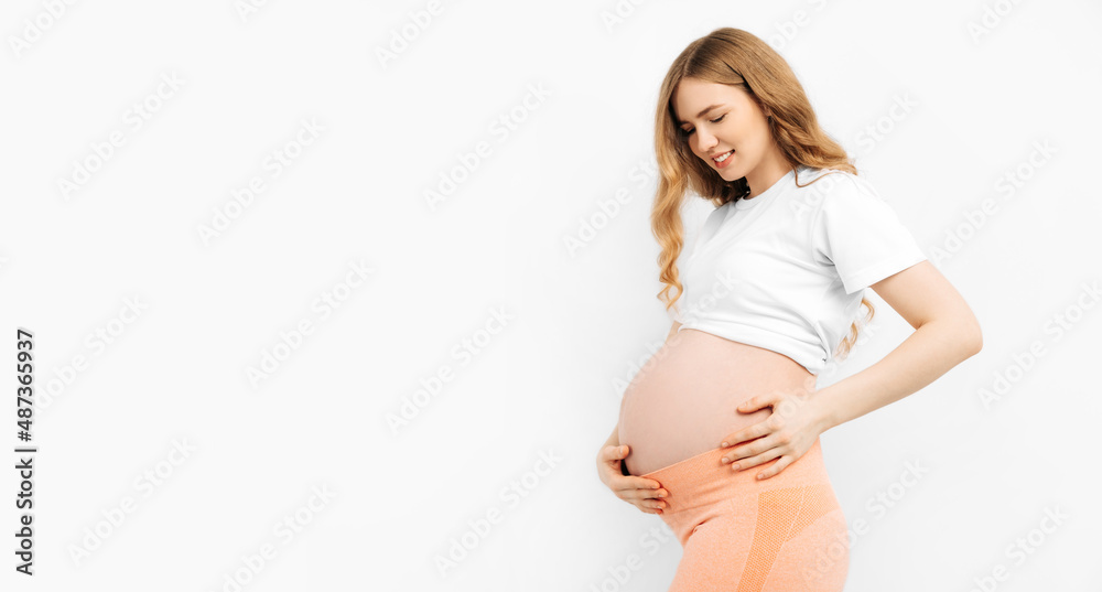 Pregnant happy woman touches her belly. Pregnant mom caressing her belly and smiling close up. Healthy pregnancy concept
