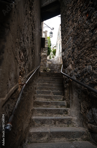 Stone steps rise up in a narrow dark passage between the walls of old houses