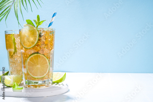 Cuba Libre, long island iced tea cocktail with strong alcohol drink, cola, lime and ice in two glass, cold longdrink mocktail on light blue tiled background