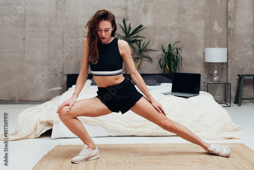 Woman practicing at home doing leg stretching exercises