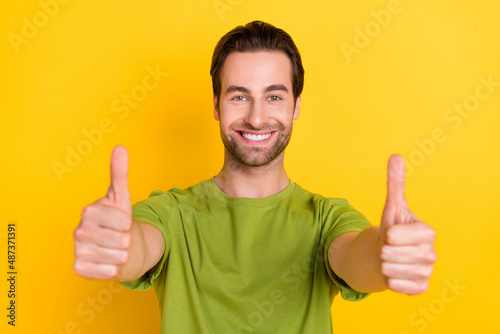 Photo of impressed beard millennial guy show thumb up wear green t-shirt isolated on yellow color background © deagreez
