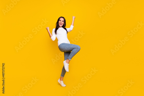 Full size photo of young cheerful girl rejoice luck fists hands awesome isolated over yellow color background