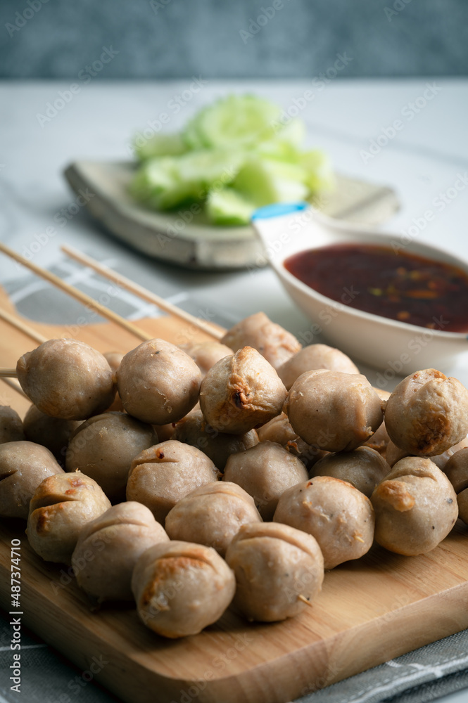 Grilled pork balls with spicy sauce on woodplate and cocumber thaicall Lukchinping