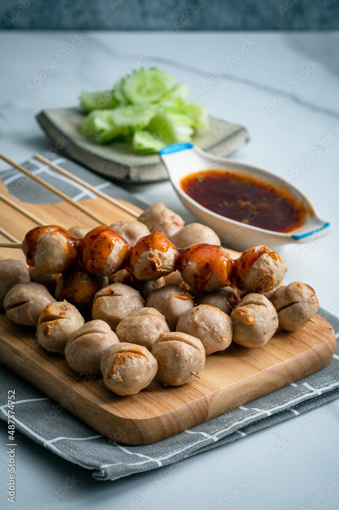 Grilled pork balls with spicy sauce on woodplate and cocumber thaicall Lukchinping Grilled pork balls with spicy sauce on woodplate and cocumber thaicall Lukchinping