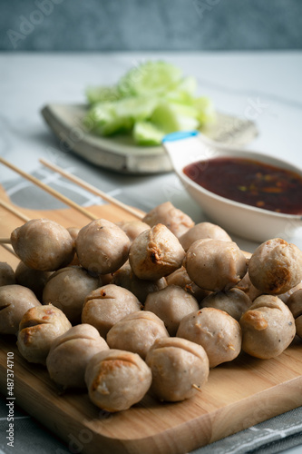 Obraz na płótnie Grilled pork balls with spicy sauce on woodplate and cocumber thaicall Lukchinping w salonie