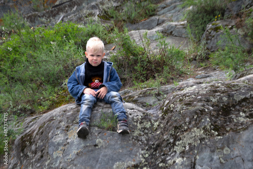 Boy sitting on a rock in the mountains