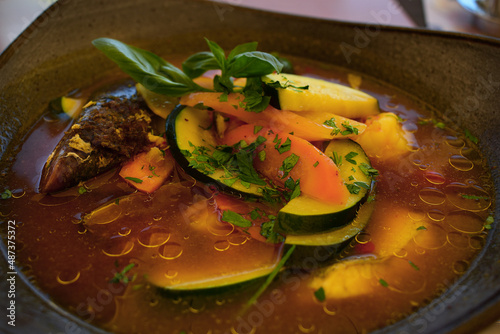 Fischsuppe mit Zucchini, Muscheln, Schrimps, Garnelen, Gemüse in grauer Suppenschüssel photo