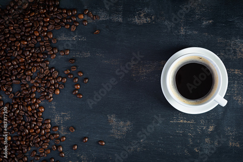 Cup of coffee with coffee beans on dark background. Mug of hot drink coffee
