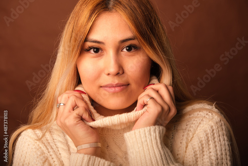 A woman of Asian appearance on a brown background